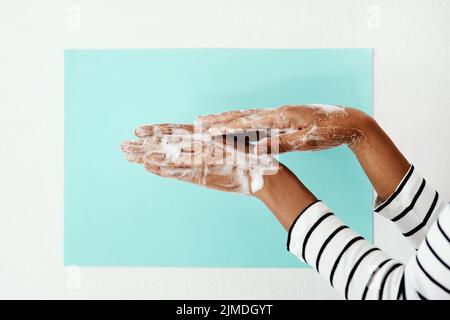 Aufschäumen wie dein Leben davon abhängt. Eine Frau, die sich vor einem Studiohintergrund die Hände mit Seife wäscht. Stockfoto