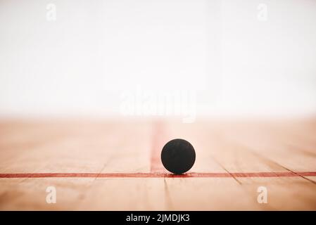 Ich hüpfte in kürzester Zeit herum. Ein Squashball auf dem Boden eines Squashplatzes. Stockfoto