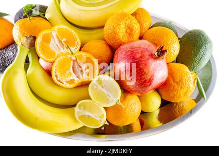 Verschiedene Obst- und Gemüseteller mit Bananen, Granatapfel, Zitrone, Mandarine und Avocado. Stockfoto