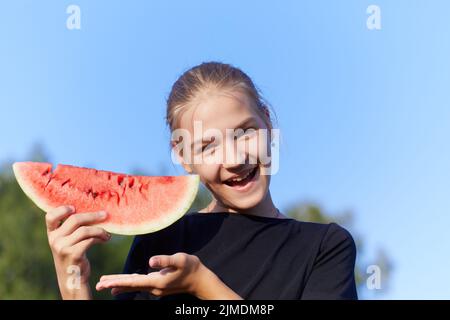 Glückliches junges Mädchen mit Wassermelone auf blauem Himmel Hintergrund Stockfoto