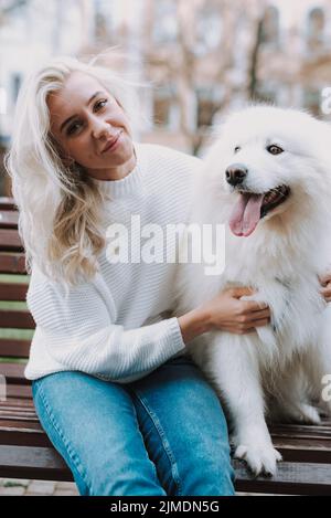 Glückliche hübsche Hündin umarmt ihren samoyed Hund Stockfoto