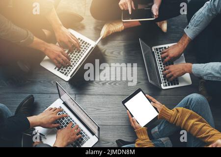Über der Gruppe von Kollegen, die an einem Projekt oder einer geschäftlichen Besprechung mit drahtloser Technologie zusammenarbeiten. Draufsicht auf ein vielfältiges Team-Brainstorming in einem Stockfoto