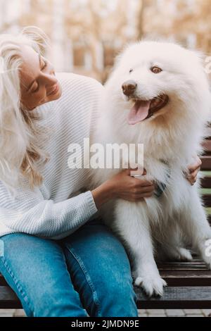 Hübsche Frau umarmt ihren samoyed Hund Stockfoto