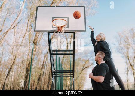 Junges Paar in schwarzer Sportkleidung, das Basketball spielt Stockfoto