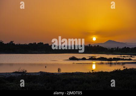 Sonnenuntergang am Salzsee von Larnaca mit untergehenden Sonne und Windturbinen in der Ferne Stockfoto