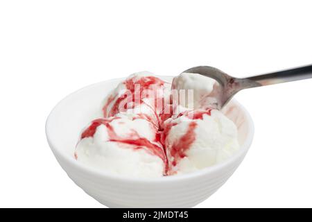 Kugeln aus weißem Eis mit Rotbeersirup in einer weißen Schüssel auf weißem Hintergrund Stockfoto