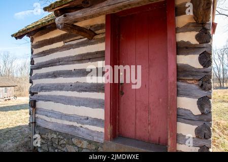 Colonial Pennsylvania Blockhütte außen mit roter Tür Stockfoto