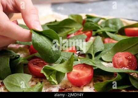 Pizza mit Käse, Tomaten, Spinat und Räucherwurst Stockfoto