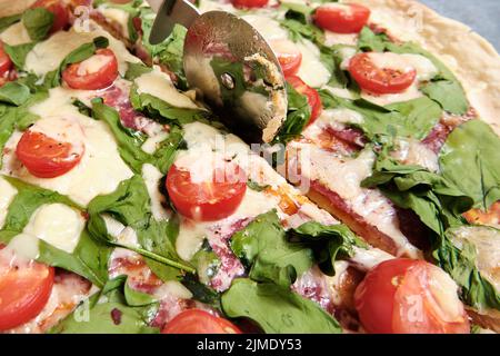 Pizza mit Käse, Tomaten, Spinat und Räucherwurst Stockfoto