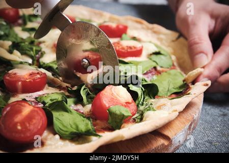 Pizza mit Käse, Tomaten, Spinat und Räucherwurst Stockfoto
