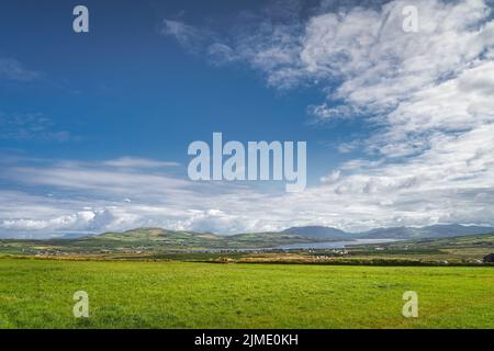 Blick von den Kerry Cliffs auf grüne Felder oder Weiden, Berge und Portmagee Village Stockfoto