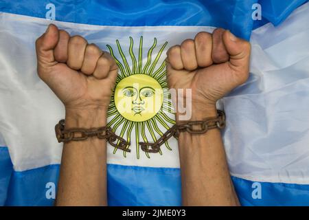 Fäuste, die die Ketten auf der argentinischen Flagge brechen. Argentinische Revolution und Unabhängigkeitskonzept Stockfoto