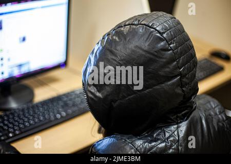 Ein Hacker sitzt an einem Computer. Anonymes Internet. Stockfoto