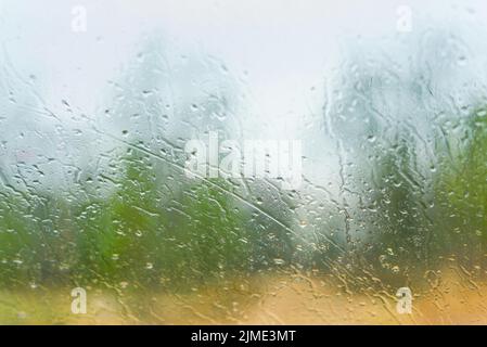 Regentropfen auf dem nassen transparenten Glas. Unscharfer Hintergrund Stockfoto