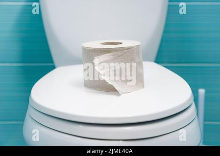 Zerrissene Rolle Toilettenpapier liegt auf dem geschlossenen Deckel der Toilettenschüssel Stockfoto