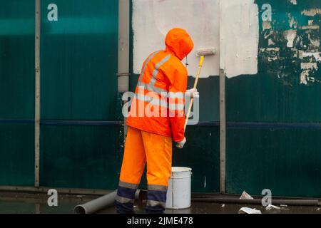 Der Maler malt mit weißer Farbe. Malt Graffiti mit Farbe. Stockfoto