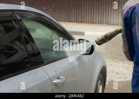 Autowäsche. Das Auto wird unter dem Druck eines Wasserstrahls gewaschen. Stockfoto