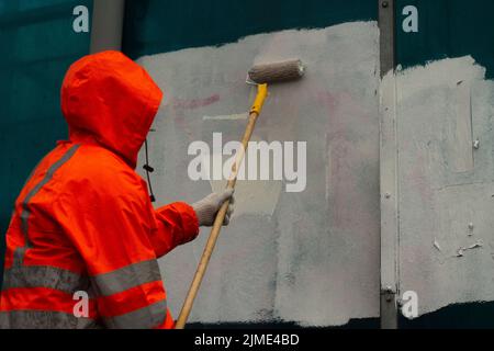 Der Maler malt mit weißer Farbe. Malt Graffiti mit Farbe. Stockfoto