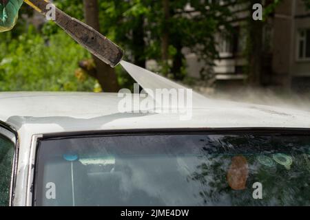 Wäscht das Dach des Fahrzeugs. Der Wasserfluss vom Schlauch zum Auto. Stockfoto