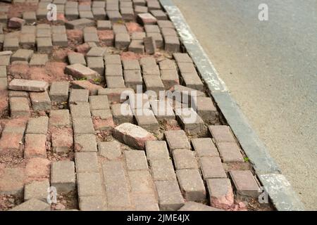 Gebrochene Pflastersteine auf der Straße. Das Mauerwerk ist gebrochen. Stockfoto