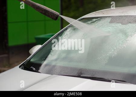 Autowäsche. Das Auto wird unter dem Druck eines Wasserstrahls gewaschen. Stockfoto