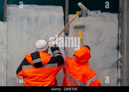 Der Maler malt mit weißer Farbe. Malt Graffiti mit Farbe. Stockfoto