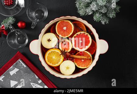 Glühwein in einem Keramikkochfeld auf einem dunklen Tisch, weihnachtliche Einrichtung, Draufsicht Stockfoto