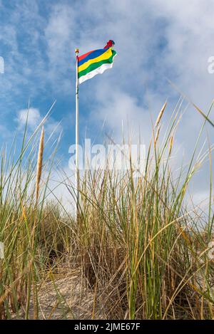 Flagge von Terschelling auf einer Düne gegen einen blauen Himmel mit weißen Wolken Stockfoto