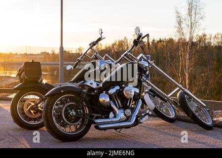 2 lange Gabel Chopper Harley Davidson Motorräder Seite an Seite in der Abendsonne. Nicht werksseitig, selbstgebaut. Stockfoto