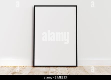 Leerer dünner schwarzer Rahmen auf hellem Holzboden mit weißer Wand dahinter. Stockfoto