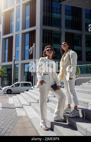 Zwei Freundinnen ruhen sich aus, nachdem sie in der Stadt in der Nähe des Geschäftszentrums gestanden haben Stockfoto