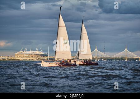 Russland, St.Petersburg, 23. Juli 2021: Wettbewerb von drei Segelbooten am Horizont im Meer bei Sonnenuntergang, der erstaunliche Sturmhimmel von di