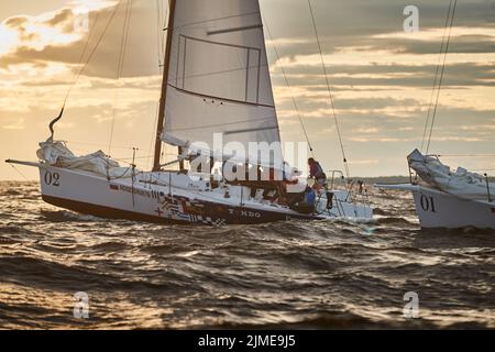 Russland, St. Petersburg, 23. Juli 2021: Wettbewerb von zwei Segelbooten am Horizont im Meer bei Sonnenuntergang, der erstaunliche Sturmhimmel von Dif Stockfoto