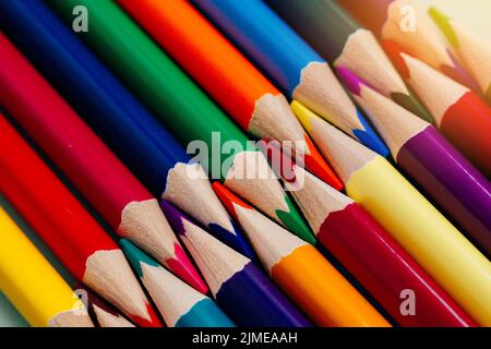 Farbige, geschärfte Stifte liegen in einer Reihe in Nahaufnahme. Solider abstrakter Hintergrund aus mehrfarbigen Holzstiften. Stockfoto