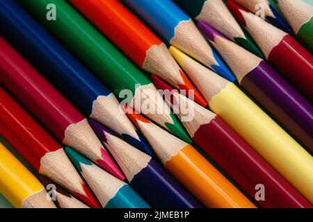 Farbige, geschärfte Stifte liegen in einer Reihe in Nahaufnahme. Solider abstrakter Hintergrund aus mehrfarbigen Holzstiften. Stockfoto