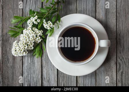 Tasse Kaffee mit Frühlingsblumen auf Holztisch, hochkellig Stockfoto