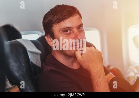 Glücklich lächelnd träumen unrasiert Menschen Person Mann mit 40+ Jahren mit Stoppeln sitzt auf einem Flugzeug während eines Fluges vom Flughafen zu reisen. spe Stockfoto