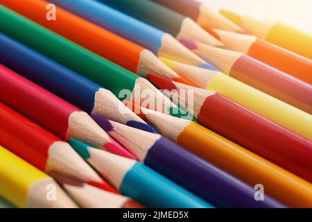 Farbige, geschärfte Stifte liegen in einer Reihe in Nahaufnahme. Solider abstrakter Hintergrund aus mehrfarbigen Holzstiften. Stockfoto