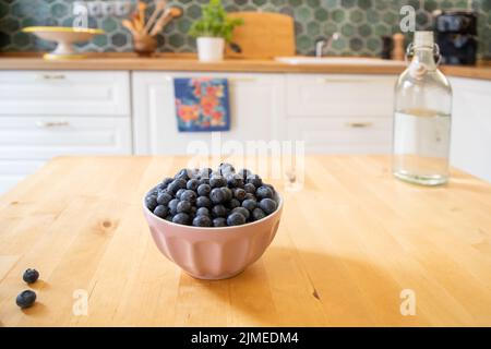 Schale mit frischen Blaubeeren auf rustikalem Küchentisch Stockfoto