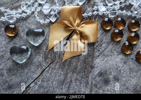 Glänzend goldenen Bogen, transparente Herzen und Perlen auf den rauen Hintergrund ein alter Baumstumpf mit einer Gaumenspalte Stockfoto