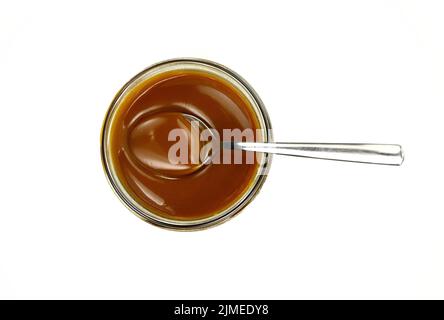 Süße Karamellsauce in einer transparenten Schüssel isoliert auf weißem Hintergrund Nahaufnahme. Golden Butterscotch Toffee Karamell Flüssigkeit. Geschmolzene Karamellsoße tropfen. Stockfoto