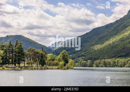 Sanfter Hang zu einem hohen Bergsee Lago d'Idro, überwuchert mit immergrünen Nadelbäumen und Laubbäumen. Brescia, Lombardei, Italien Stockfoto