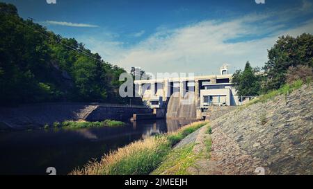 Ein Damm auf dem Brünner Stausee am Fluss Svratka mit einem kleinen Kraftwerk. Schöner sonniger Sommertag in der Natur. Stockfoto