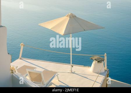 Zwei Sonnenliegen und ein Sonnenschirm auf dem Balkon von Santorini Stockfoto