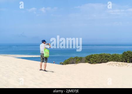 Ein Mann macht ein Foto auf der Düne mit Blick auf das Becken. Wiedereröffnung der Dune du Pilat und ihrer Touristen nach dem Brand. Frankreich, Le-Pyla-sur Mer, La Teste-De-Buch. 4. August 2022. Foto von Patricia Huchot-Boissier/ABACAPRESS.COM Stockfoto