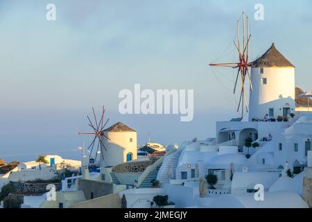 Windmühlen und Weiße Häuser auf einem Berghang in Santorini Stockfoto