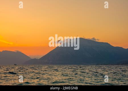 Windfarmen und eine Wolke auf einer bergigen Küste bei Sonnenuntergang Stockfoto