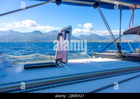 Blick von der Seite einer Segelyacht auf eine hügelige Küste Stockfoto