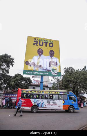 Nairobi, Kenia. 3. August 2022. Ein Matatu (Minibus) fährt in der Nähe einer Plakatwand für politische Kampagnen mit einem Bild des stellvertretenden Präsidenten Kenias William Ruto, Präsidentschaftskandidat der Vereinigten Demokratischen Allianz (UDA), und seines Laufgefährten Ragathi Gachaguain Nairobi vorbei, während die Kenianer sich auf die Wahlen vom 9.. August 2022 vorbereiten. Politiker führen in verschiedenen Teilen des Landes weiterhin Kampagnen durch, um Stimmen von Kenianern zu erhalten. Plakate, Plakate, Markenautos, Regenschirme, T-Shirts und Banner für politische Kampagnen sind überall im Wahlkampf zu sehen. Die Kenianer werden am 9. August an den Wahlurnen teilnehmen. Stockfoto