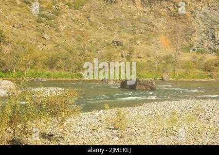 Ein riesiger Stein in der Mitte eines wunderschönen türkisfarbenen Flusses, der am Grund einer tiefen Schlucht fließt. Chulyschman Fluss, Altai, Sibirien, Russland. Stockfoto